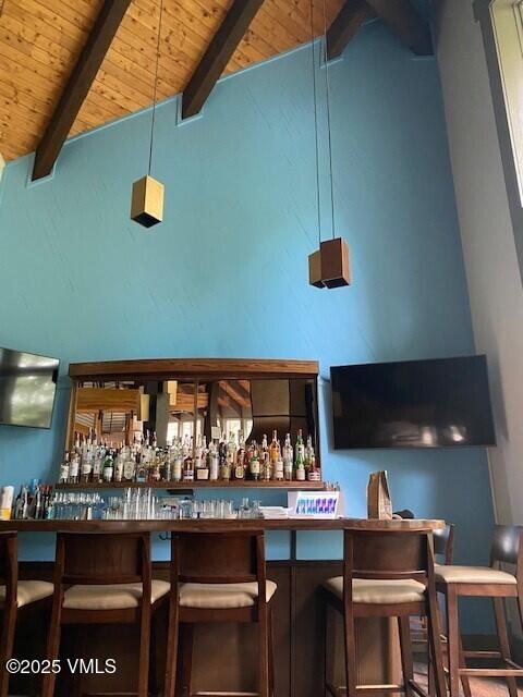 bar featuring high vaulted ceiling, wooden ceiling, and beamed ceiling