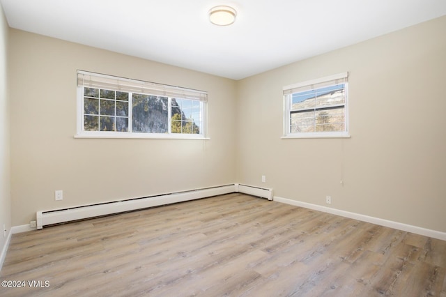 spare room featuring light hardwood / wood-style flooring, a wealth of natural light, and a baseboard radiator