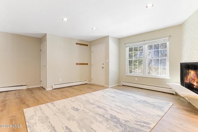 unfurnished living room with a baseboard heating unit, light hardwood / wood-style flooring, and a brick fireplace