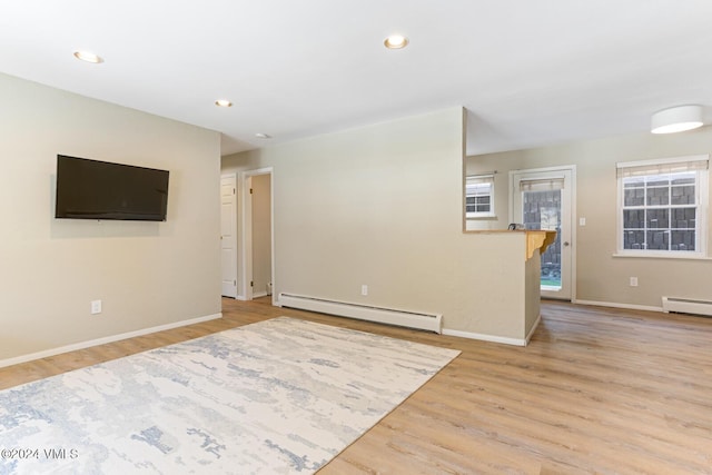 unfurnished living room featuring baseboard heating and light hardwood / wood-style flooring