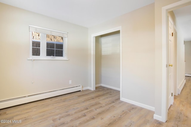 spare room featuring a baseboard radiator and light wood-type flooring