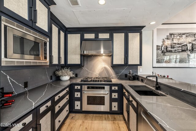 130 Daybreak Rd Unit R401, Beaver Creek, CO 81620 - kitchen with stainless steel appliances, a sink, range hood, light wood-style floors, and decorative backsplash