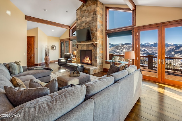 living room with hardwood / wood-style floors, beam ceiling, plenty of natural light, high vaulted ceiling, and a stone fireplace