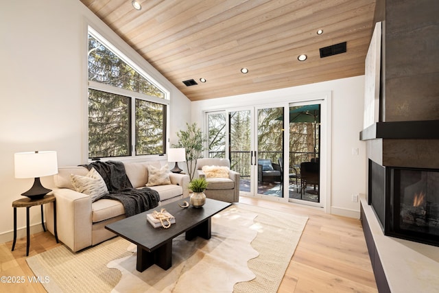 living area featuring visible vents, a multi sided fireplace, light wood-style floors, and wooden ceiling