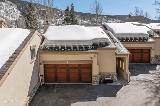 view of front of home with aphalt driveway, stone siding, and an attached garage