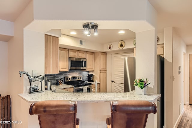 55 River Pines Ct Unit A204, Edwards, CO 81632 - kitchen featuring appliances with stainless steel finishes, light brown cabinetry, tasteful backsplash, a peninsula, and recessed lighting