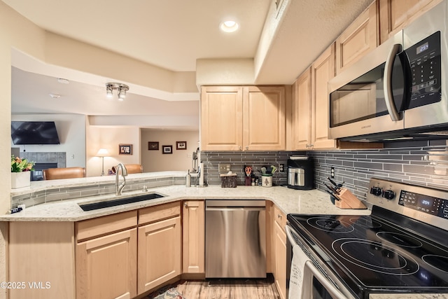 55 River Pines Ct Unit A204, Edwards, CO 81632 - kitchen with appliances with stainless steel finishes, light brown cabinetry, light stone countertops, a peninsula, and decorative backsplash