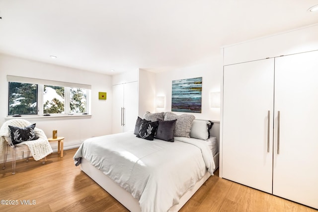 bedroom with multiple closets and light hardwood / wood-style flooring