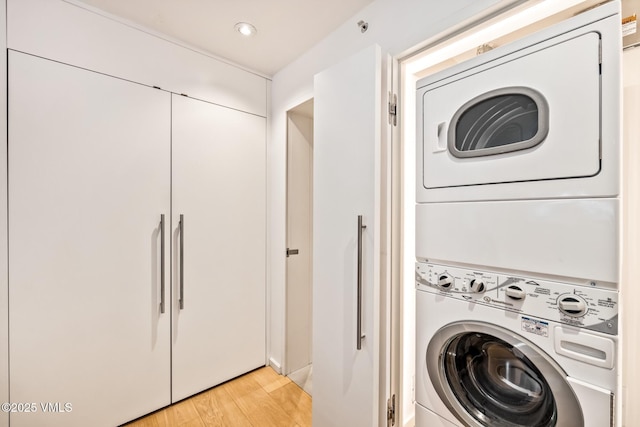 laundry area with stacked washing maching and dryer and light hardwood / wood-style floors