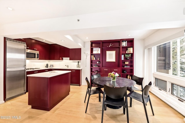 kitchen with a kitchen island, appliances with stainless steel finishes, sink, and light hardwood / wood-style floors