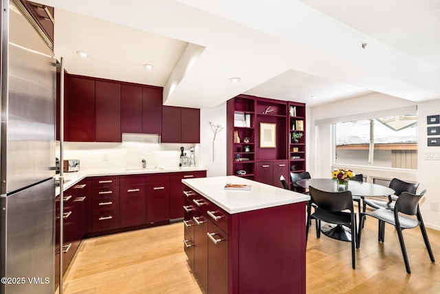 kitchen featuring sink, stainless steel fridge, light hardwood / wood-style floors, and a kitchen island