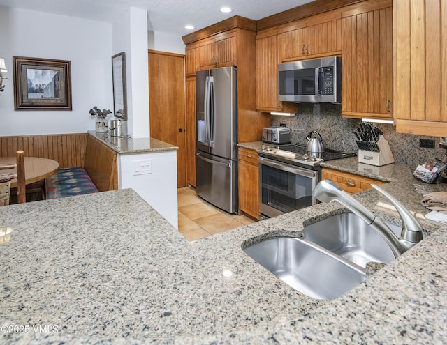 120 Offerson Rd Unit 6140, Beaver Creek, CO 81620 - kitchen with appliances with stainless steel finishes, brown cabinetry, light stone countertops, backsplash, and light tile patterned flooring