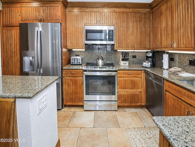 120 Offerson Rd Unit 6140, Beaver Creek, CO 81620 - kitchen featuring appliances with stainless steel finishes, tasteful backsplash, light stone countertops, and brown cabinetry