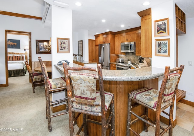 120 Offerson Rd Unit 6140, Beaver Creek, CO 81620 - kitchen featuring stainless steel appliances, brown cabinets, a kitchen breakfast bar, tasteful backsplash, and recessed lighting