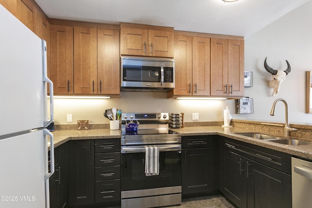 kitchen featuring a sink, light stone countertops, brown cabinets, and stainless steel appliances