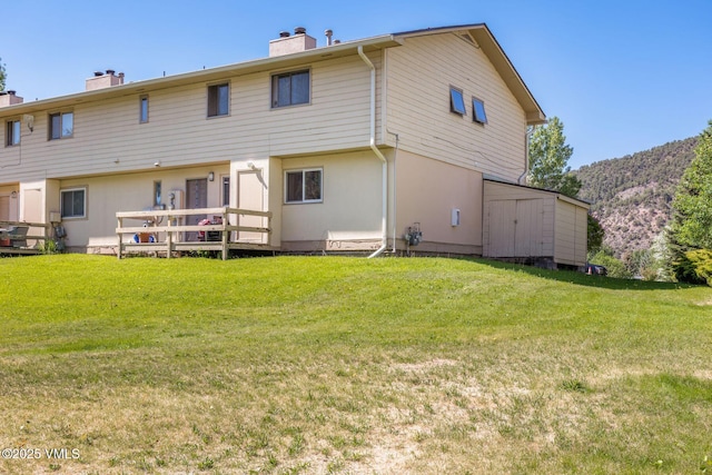 600 Price Ln Unit 1, Gypsum, CO 81637 - back of house featuring a chimney, a yard, a storage shed, and a deck with mountain view