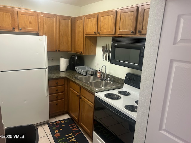 kitchen featuring black microwave, a sink, freestanding refrigerator, electric stove, and light tile patterned flooring