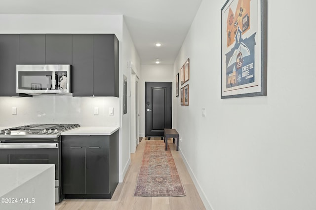 kitchen with tasteful backsplash, stainless steel appliances, and light hardwood / wood-style floors