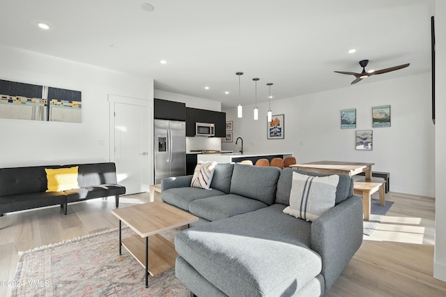 living room featuring ceiling fan, sink, and light hardwood / wood-style floors