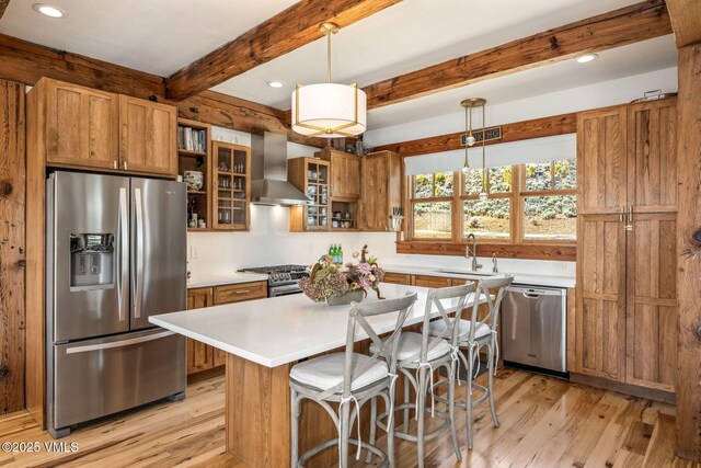 674 Hernage Creek Rd, Eagle, CO 81631 - kitchen with appliances with stainless steel finishes, wall chimney range hood, light wood finished floors, brown cabinetry, and beamed ceiling