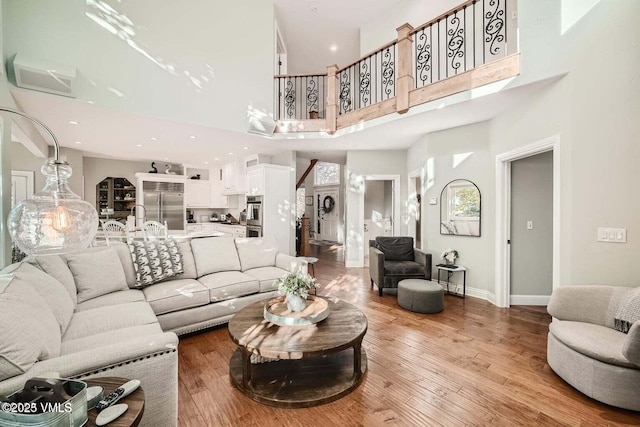 living area featuring a high ceiling, recessed lighting, wood finished floors, and baseboards