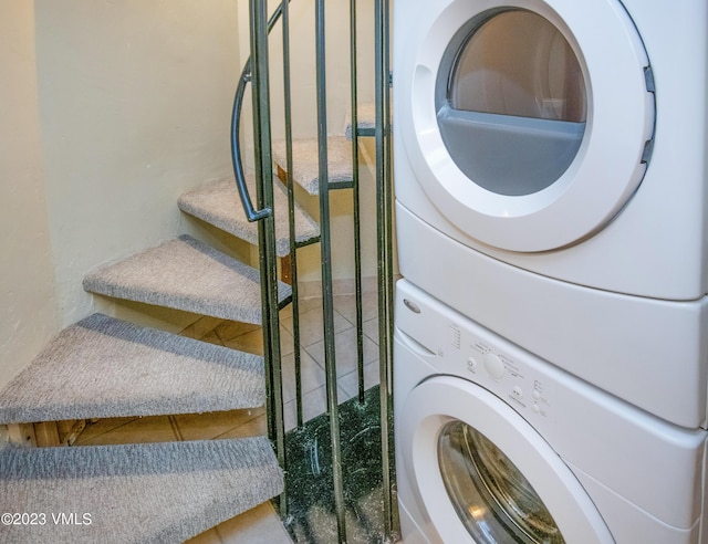 clothes washing area featuring tile patterned floors, stacked washer and clothes dryer, and laundry area