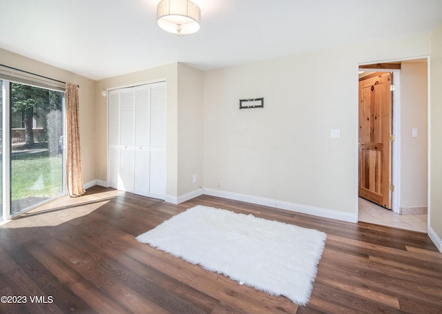 unfurnished bedroom with baseboards, wood finished floors, and a closet