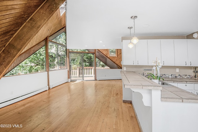 interior space featuring recessed lighting, vaulted ceiling, baseboard heating, light wood finished floors, and a sink