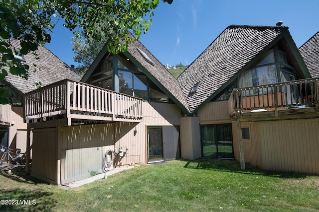 back of property featuring a yard, a wooden deck, and a sunroom
