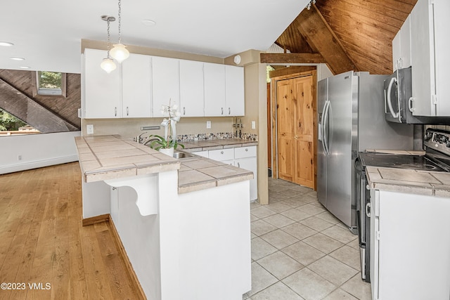 kitchen with stainless steel appliances, a peninsula, baseboards, pendant lighting, and white cabinets