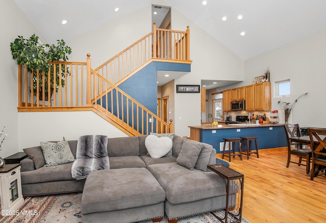 living room with high vaulted ceiling and light wood-type flooring