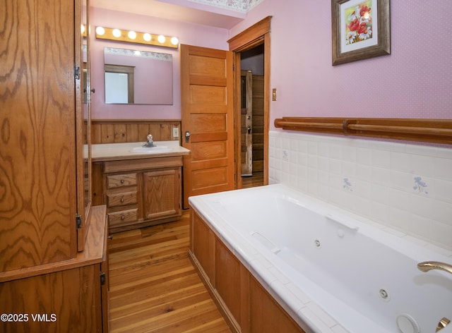 409 Washington St, Eagle, CO 81631 - bathroom with wood finished floors, vanity, a jetted tub, and wainscoting