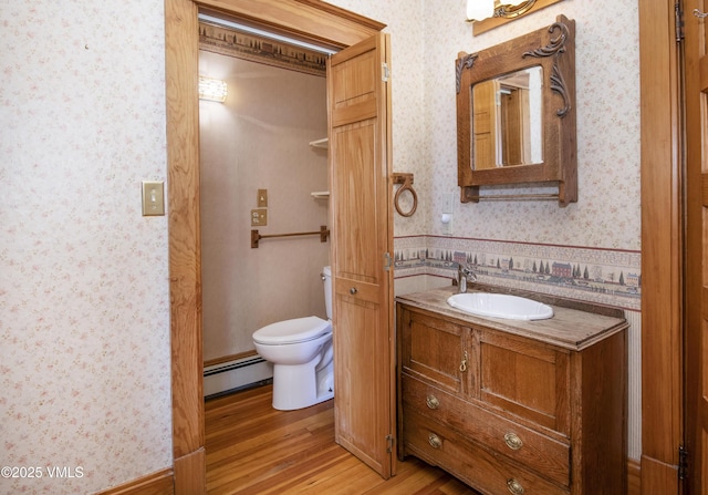 409 Washington St, Eagle, CO 81631 - bathroom featuring a baseboard radiator, wallpapered walls, wood finished floors, toilet, and vanity