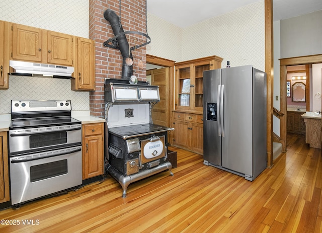 409 Washington St, Eagle, CO 81631 - kitchen with stainless steel appliances, under cabinet range hood, wallpapered walls, light wood-style flooring, and light countertops
