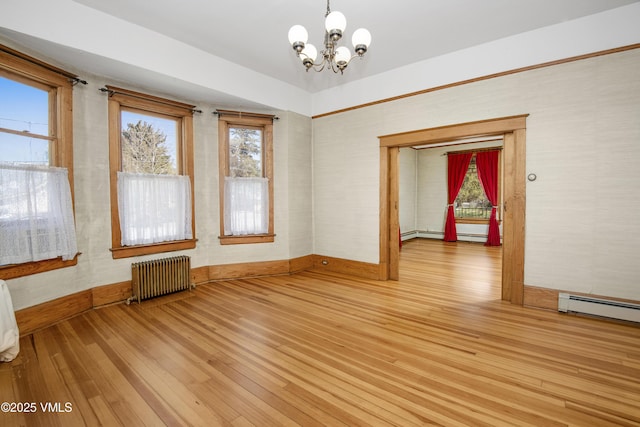 409 Washington St, Eagle, CO 81631 - empty room with radiator heating unit, light wood-style flooring, a chandelier, baseboards, and baseboard heating