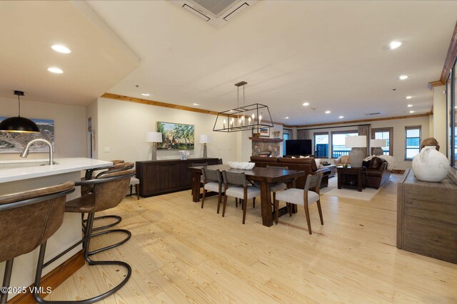 dining space featuring sink, crown molding, and light hardwood / wood-style flooring