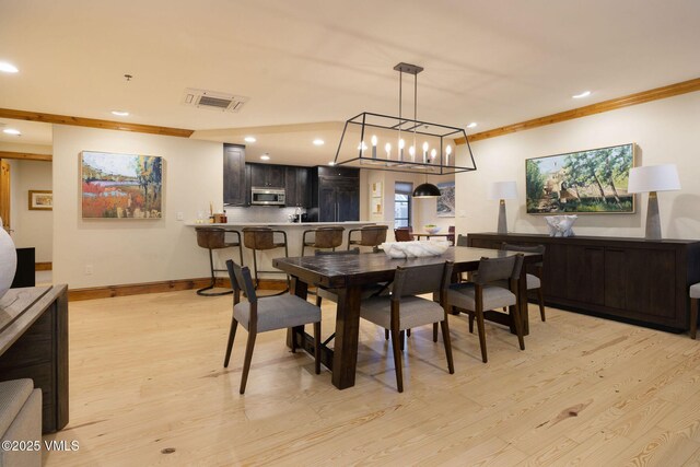 dining room with crown molding and light wood-type flooring