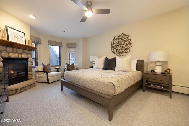 carpeted bedroom featuring ceiling fan and a fireplace