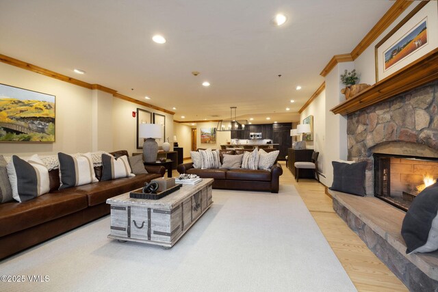 living room with ornamental molding, a stone fireplace, and light wood-type flooring