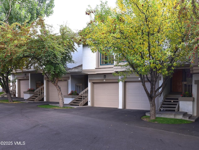931 Singletree Rd Unit 21, Edwards, CO 81632 - view of property hidden behind natural elements featuring stairway, stucco siding, asphalt driveway, and a garage