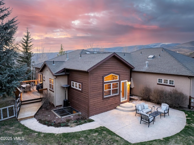 50 Andover Trl, Edwards, CO 81632 - back of house at dusk with a wooden deck, outdoor lounge area, a patio area, a shingled roof, and stucco siding