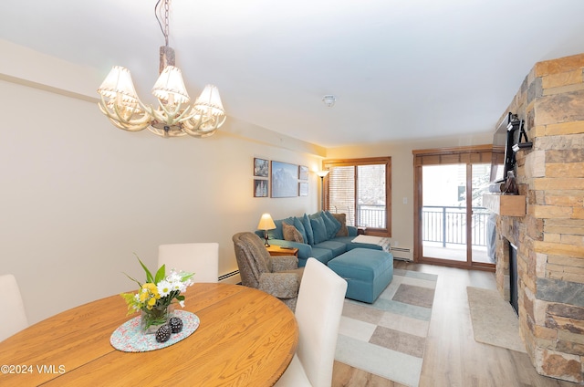 dining space featuring baseboard heating, a fireplace, light hardwood / wood-style flooring, and a notable chandelier