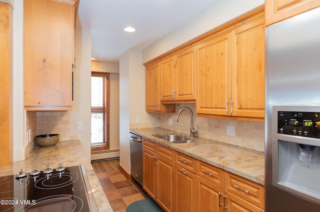 kitchen featuring sink, baseboard heating, appliances with stainless steel finishes, light stone counters, and decorative backsplash