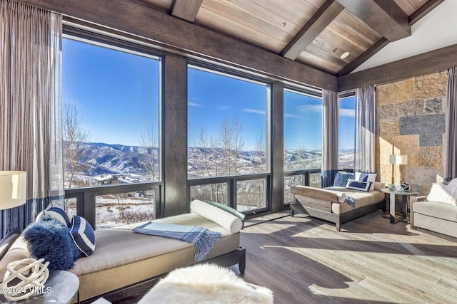 interior space with lofted ceiling with beams, expansive windows, wood finished floors, a mountain view, and wood ceiling