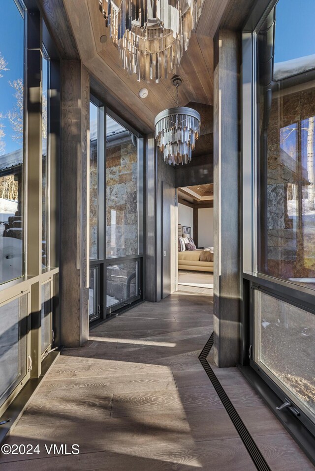 hall with a wall of windows, wood finished floors, and a chandelier