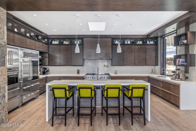 kitchen with a sink, stainless steel appliances, dark brown cabinets, and a center island with sink