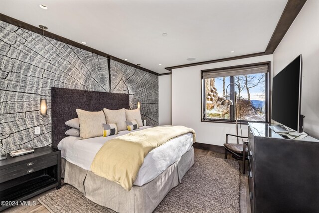 bedroom featuring recessed lighting, wood finished floors, an accent wall, and crown molding