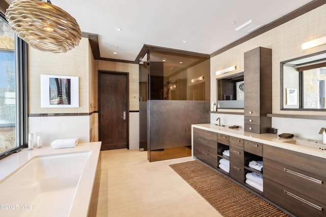 full bath featuring tile walls, a shower stall, crown molding, double vanity, and a bath