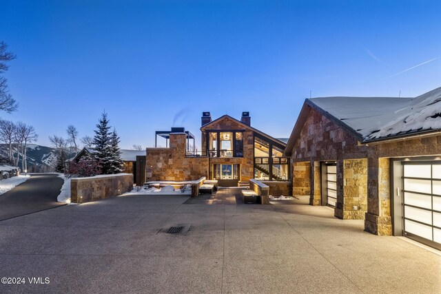 view of front facade with a patio, stone siding, and a chimney