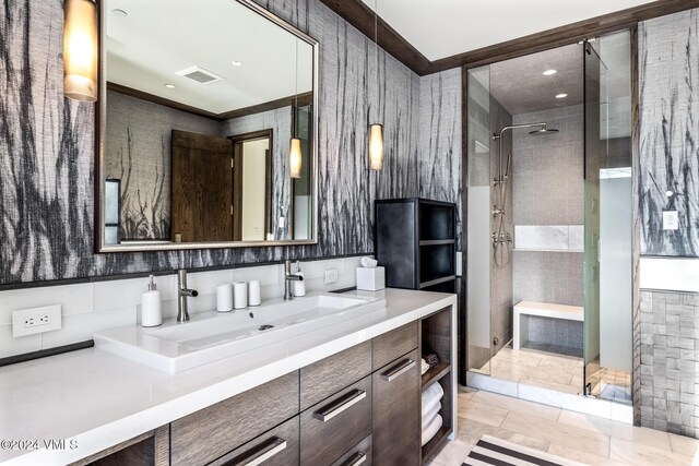 bathroom with visible vents, tiled shower, and vanity